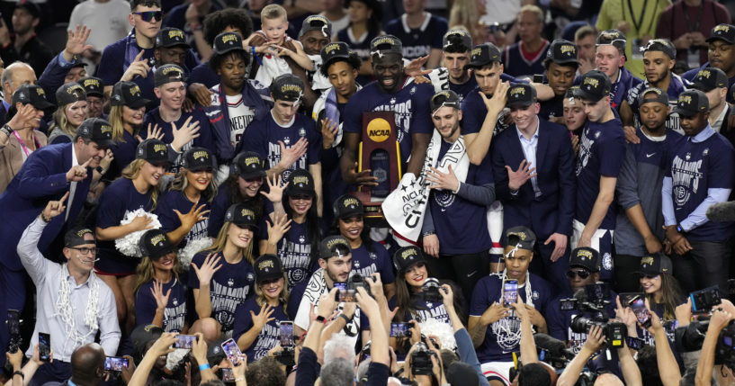 Players for UConn pose with coaches after winning the NCAA Tournament over San Diego State in Houston, Texas, on Monday night.