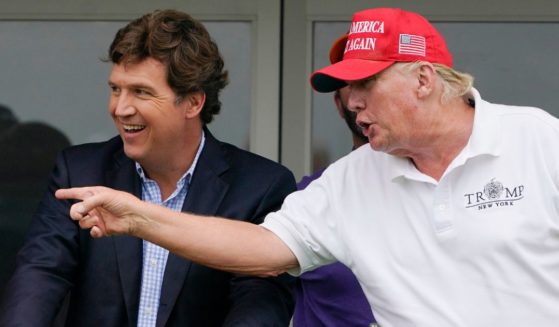 Tucker Carlson, left, and former President Donald Trump talk while watching golfers on the 16th tee during the final round of the LIV Golf Invitational at Trump National in Bedminster, New Jersey, on July 31.