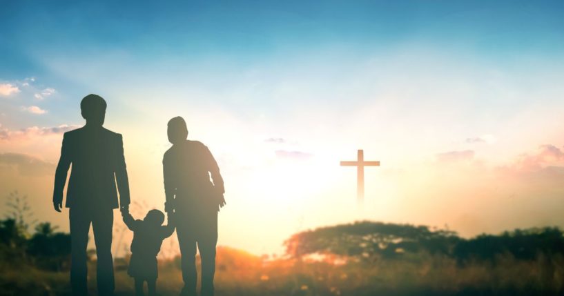 Parents hold their child's hand in this stock image.