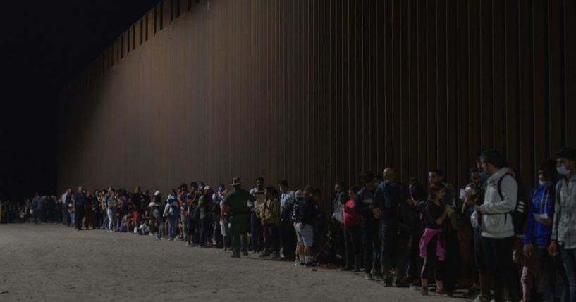 Migrants line up as they wait to be processed by US Border Patrol after illegally crossing the US-Mexico border in Yuma, Arizona, in the early morning of July 11, 2022.