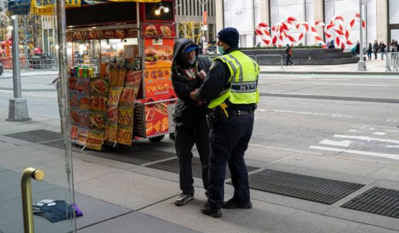 A police officer holds a man who just shoplifted several items from a clothing store December 30, 2020 in New York City. The man purposefully dropped the items as he ran into the policeman standing nearby.