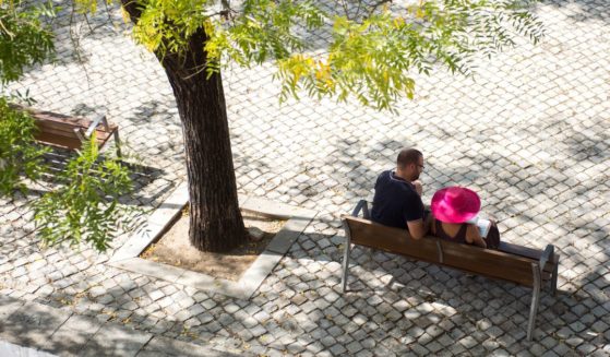 A couple sit on a bench close by the Main Church of Saint Mary of the Castle in Tavira, Portugal, on Sept. 18, 2022.