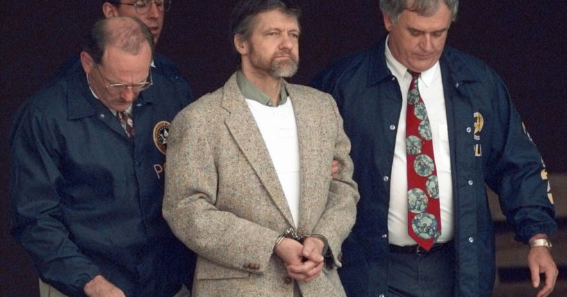 Theodore Kaczynski looks around as U.S. Marshals prepare to take him down the steps at the federal courthouse in Helena, Montana, to a waiting vehicle in a file photo from June 21, 1996. A spokesperson for the Bureau of Prisons told The Associated Press that Kaczynski, known as the “Unabomber,” has died in federal prison.