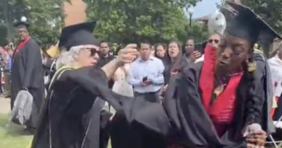 A recent college graduate rips the microphone away from a faculty member. (@rahsh33m / Twitter)