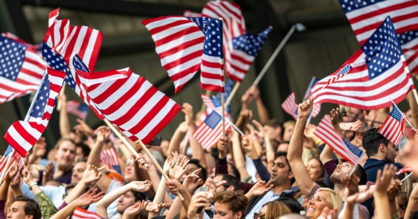 A crowd waves American flags in this stock image.