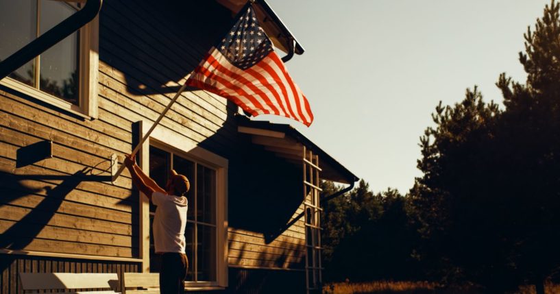 A man raises the American flag in this stock image.