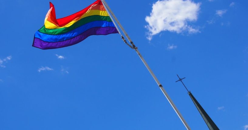 A rainbow flag flies in front of a church in this stock image.