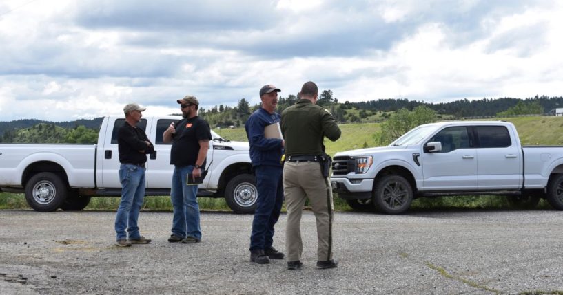 Local authorities are on the scene as heavy equipment is staged to begin removing the wreckage after a bridge collapse near Columbus, Montana, on Saturday.