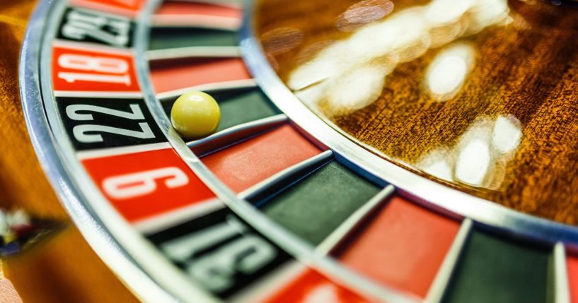 A ball rests on a roulette wheel in the above stock image.