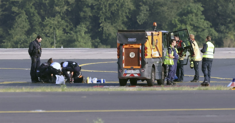 Police officers and security personnel stand on the airfield in Dusseldorf, Germany, on Thursday and try to detach activists of the group Last Generation who glued themselves to the asphalt.