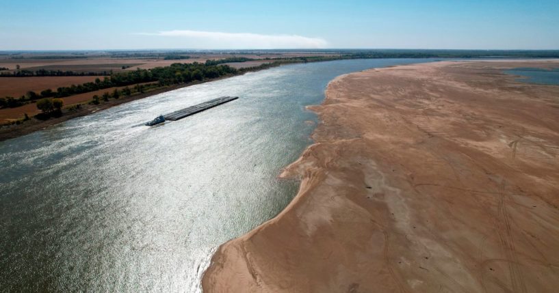 A barge maneuvers its way down the normally wide Mississippi River