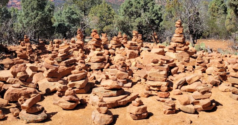 A large group of rock cairns is located at the end of a hiking trail.