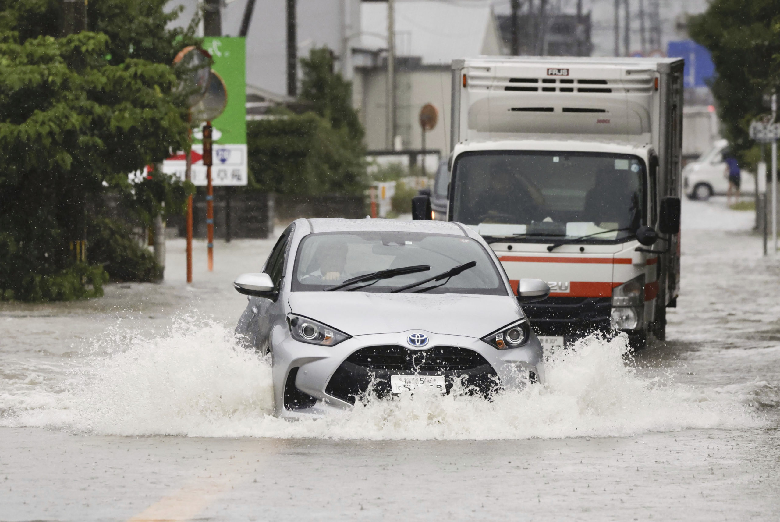 Cars plow through high water on a street in southern Japan.