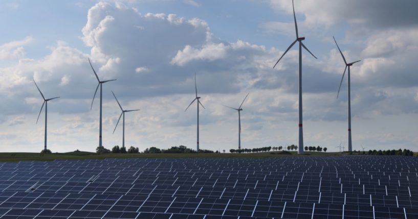 Wind turbines spin behind a solar energy park on June 2, 2022, near Prenzlau, Germany.