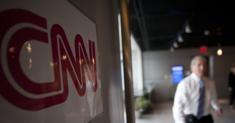 CNN Anchor John King walks past a CNN logo sign on the set of his then-Sunday morning political show "State of the Union" filmed in Washington, D.C., on Jan. 18, 2009.