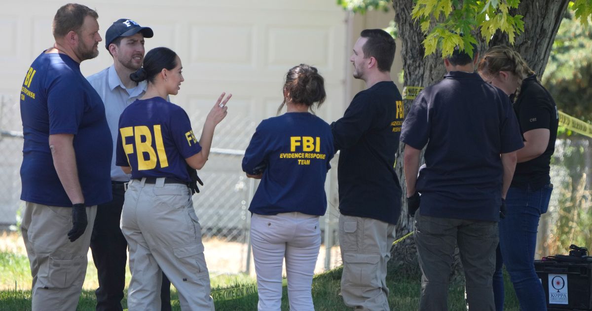 FBI officials and other law enforcement officers stand outside the home of Craig Robertson after he was shot and killed by FBI agents in a raid on his home in Provo, Utah, on Wednesday morning.