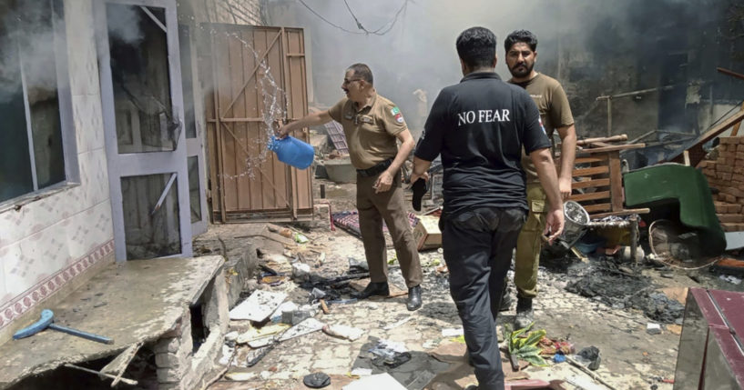 a police officer pours water into a burning house