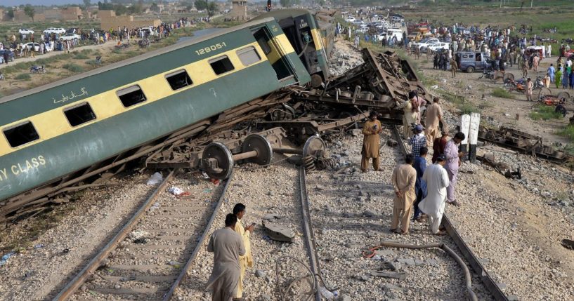 Local residents examine damaged cars of a passenger train which was derailed near Nawabshah, Pakistan, on Sunday.