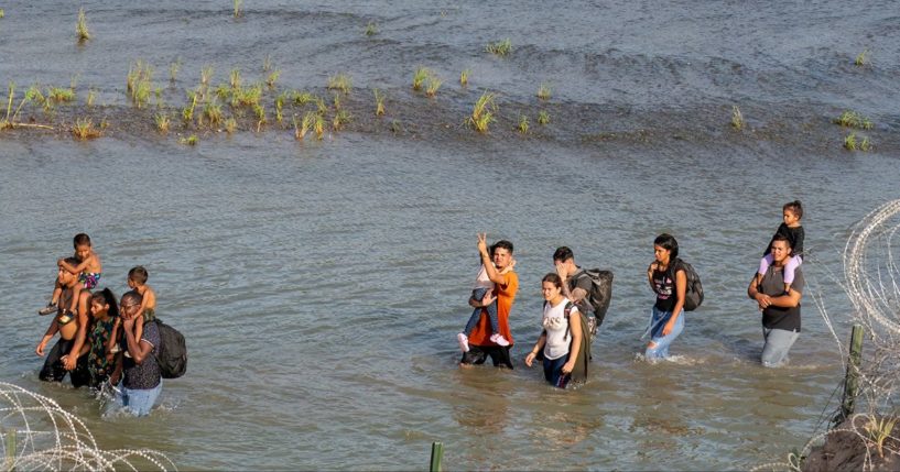 Migrants walk in the Rio Grande in Mexico, across from Eagle Pass, Texas, in a July photo.