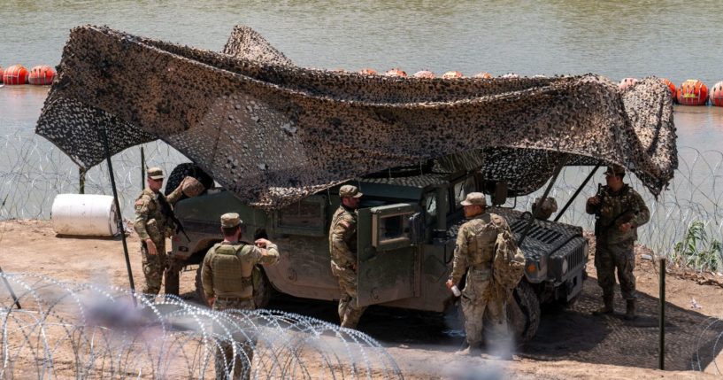 National Guard troops stand guard near a string of buoys placed on the water along the Rio Grande border with Mexico in Eagle Pass, Texas, on Aug. 24.