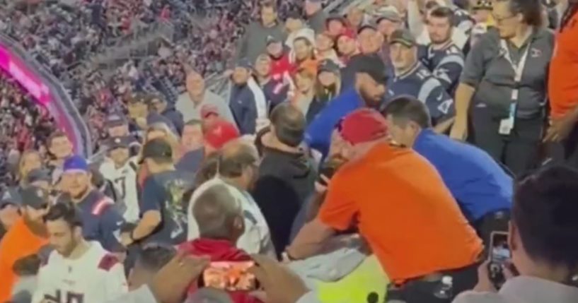 football fans fighting while bystanders try to break them up