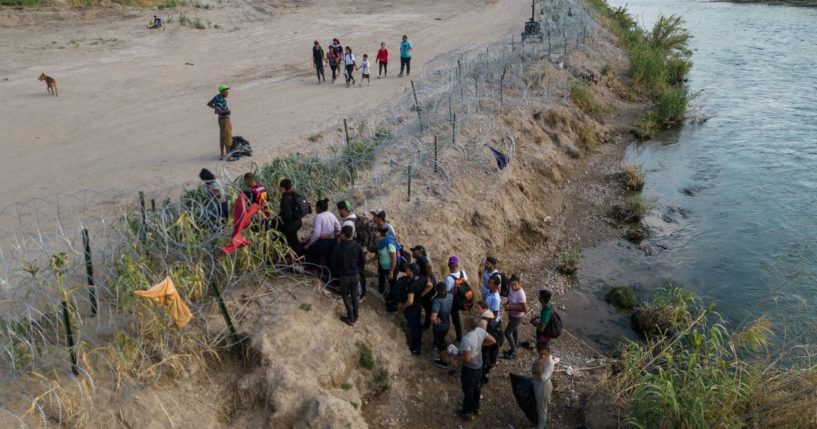 This aerial picture taken on Sunday shows a group of migrants climbing over razor wire as they cross the Rio Grande river at the US-Mexico border to Eagle Pass, Texas.