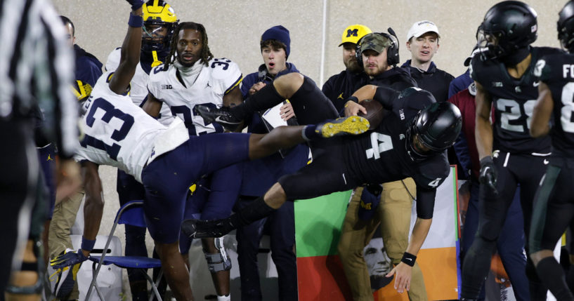 Michigan State quarterback Sam Leavitt (4) is hit out of bounds by Michigan defensive back DJ Waller Jr. (13) during the second half of an NCAA college football game, Oct. 21, 2023, in East Lansing, Michigan.