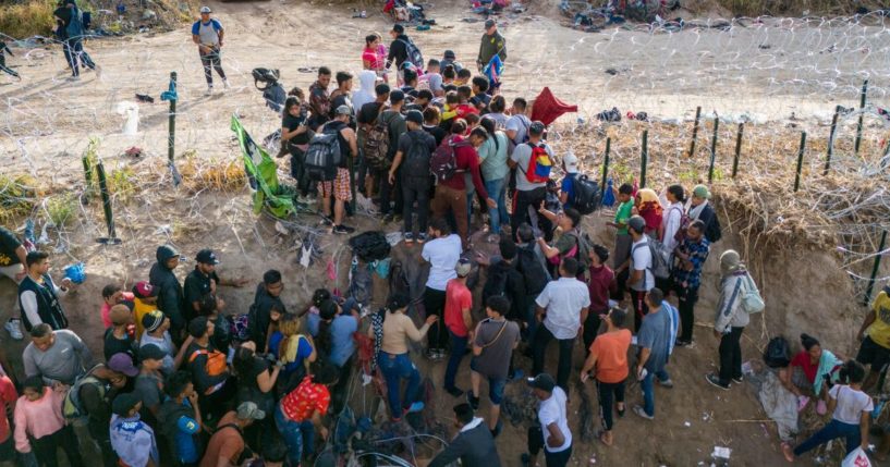 A U.S. Border Patrol agent supervises as immigrants walk into the United States near Eagle Pass, Texas, after crossing the Rio Grande from Mexico on Saturday.