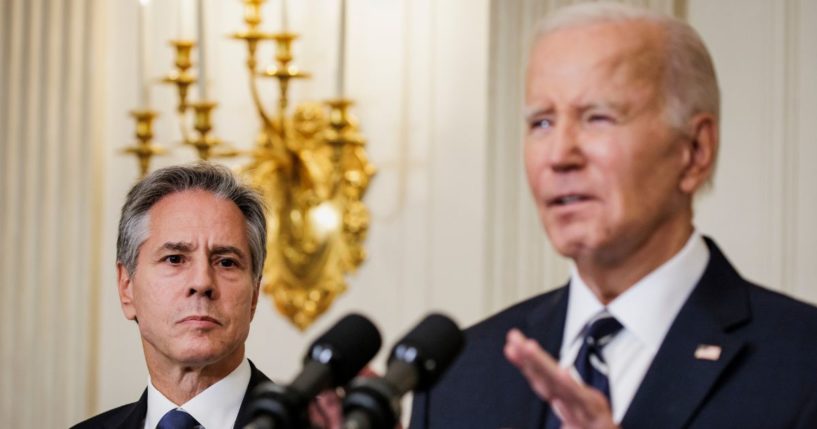 Secretary of State Antony Blinken stands alongside President Joe Biden as he delivers remarks on the terrorist attacks in Israel from the State Dining Room at the White House on Oct. 7 in Washington, D.C.