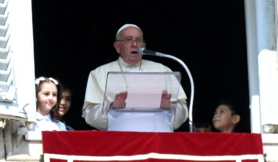 Pope Francis delivers a speech to the pilgrims flanked by children from the five continents during the Sunday Angelus prayer in St.Peter's Square at the Vatican on Sunday.