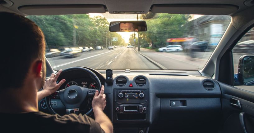 A stock photo shows a man driving a car.