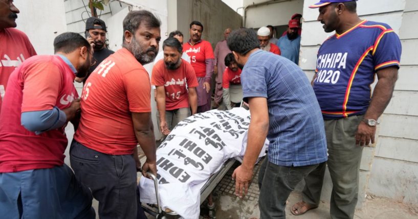 Men carry a body in Karachi, Pakistan, Saturday. At least 10 people were killed and 22 injured in the blaze at RJ Mall on Rashid Minhas Road in Karachi.