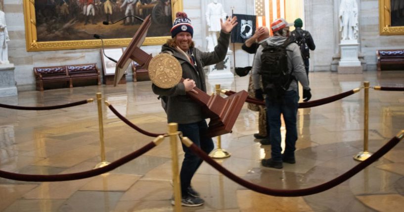 A protester identified as Adam Johnson carries the lectern of House Speaker Nancy Pelosi through the Rotunda of the U.S. Capitol Building on Jan. 6, 2021.