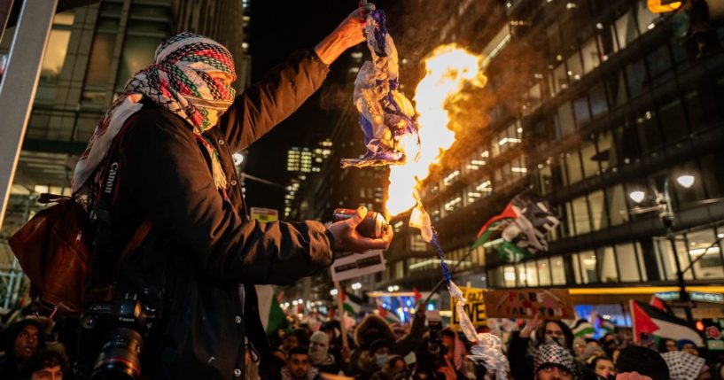 A pro-Palestinian protester burns an Israeli flag during a protest that turned violent during the lighting of the Christmas tree at Rockerfeller Center in New York City on Wednesday.