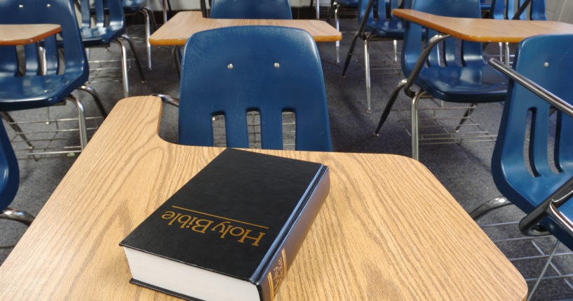 A Bible sits on a desk in a school classroom in this stock photo.