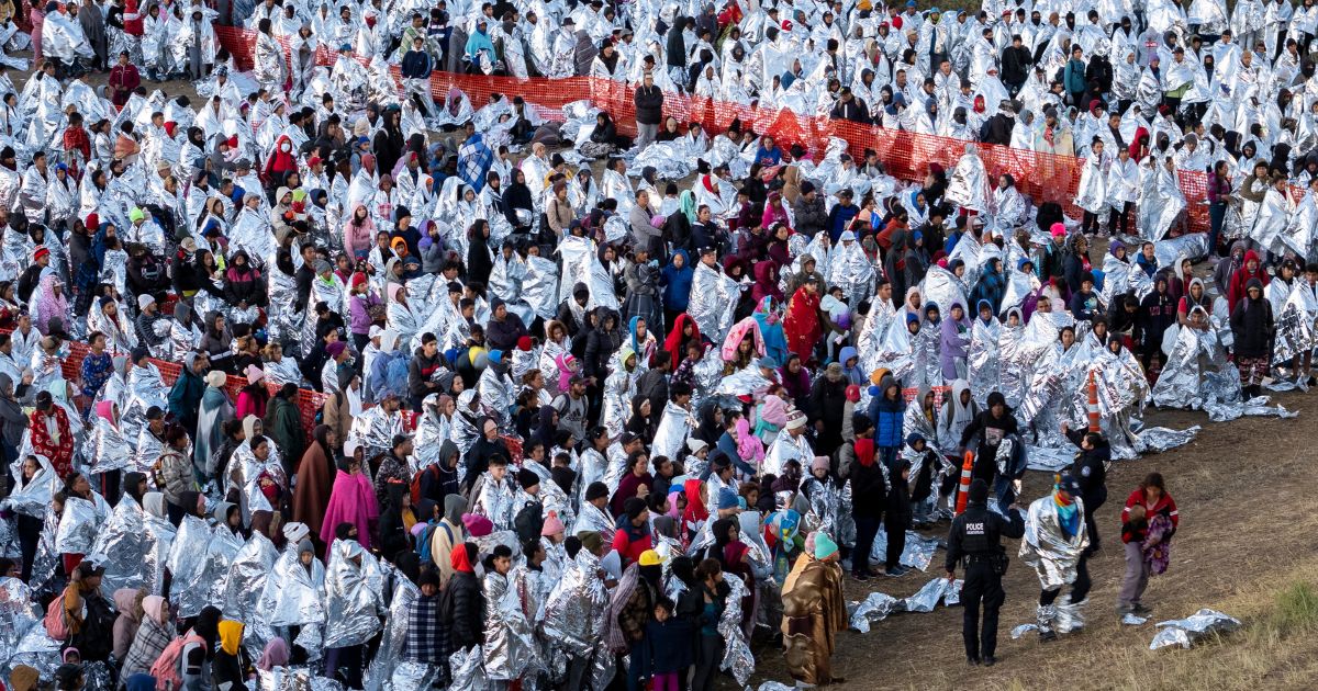 Thousands of illegal immigrants, most wearing thermal blankets, await processing at a U.S. Border Patrol transit center in Eagle Pass, Texas, on Tuesday.