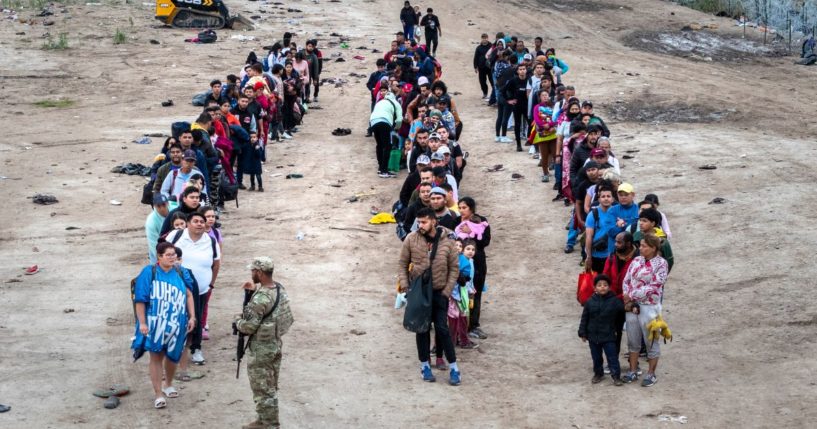 A Texas National Guard soldier speaks with immigrants after they illegally crossed the Rio Grande from Mexico on Wednesday in Eagle Pass, Texas.