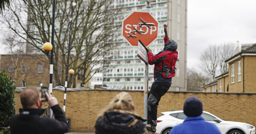 A person removes a piece of art work by Banksy at the intersection of Southampton Way and Commercial Way in Peckham, south east London, on December 22, 2023.