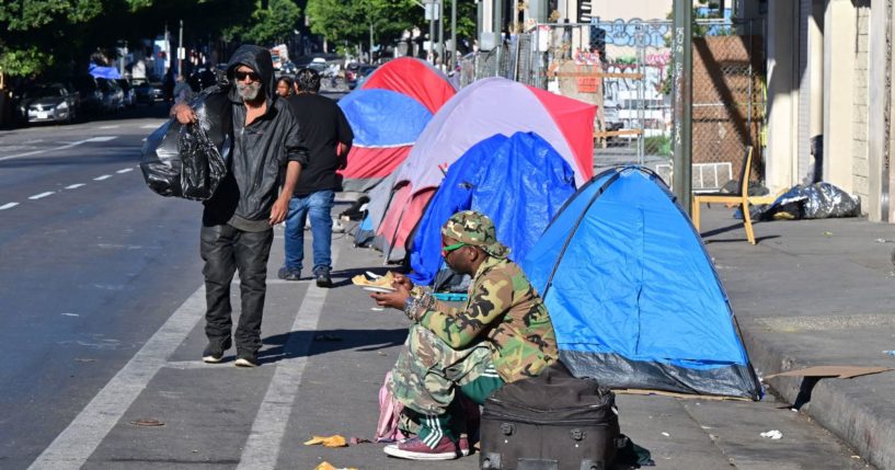 A homeless man sits on the side of a street lined with tents in Los Angeles on Nov. 22.