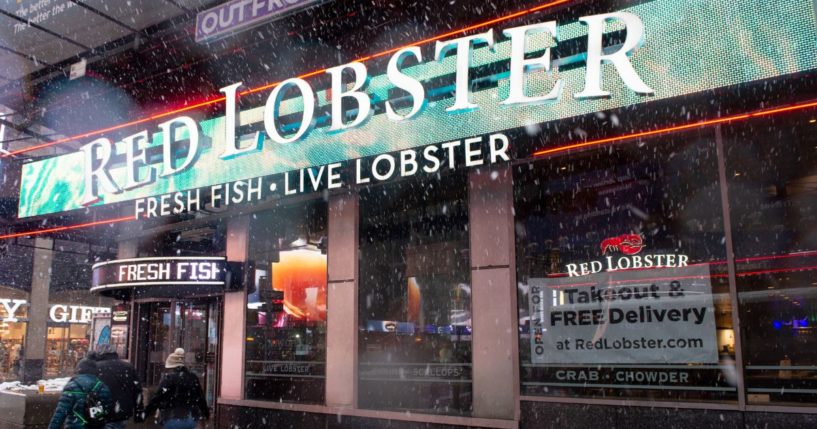 A "takeout and Free delivery" sign is displayed in the window of Red Lobster in Times Square during a snow storm on Feb. 7, 2021, in New York City.