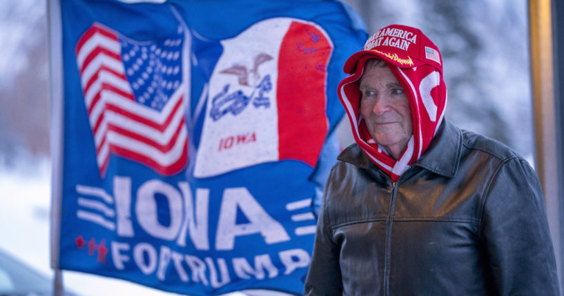 A man stands next to a flag that reads "Iowa for Trump" outside the Machine Shed in Urbandale, Iowa, on Thursday.