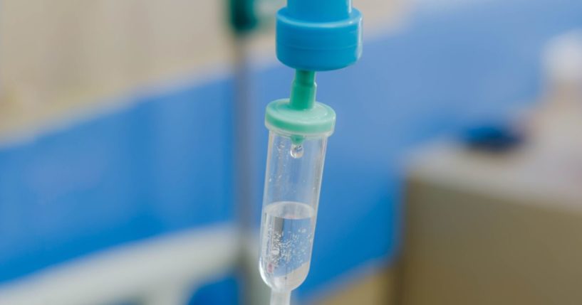 A stock photo shows a generic IV drip in a hospital room.