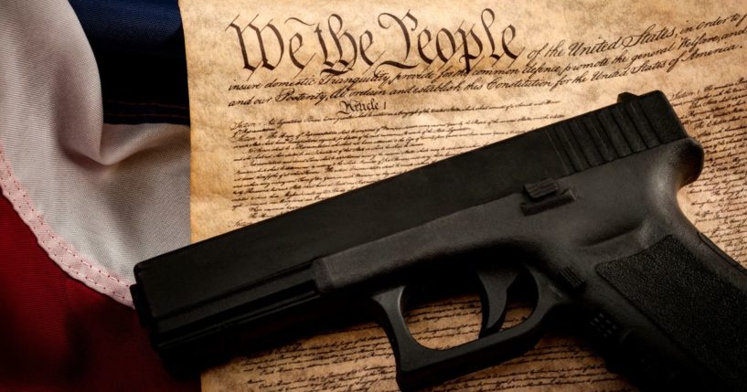 A handgun is pictured with an American flag and the U.S. Constitution in this stock photo.