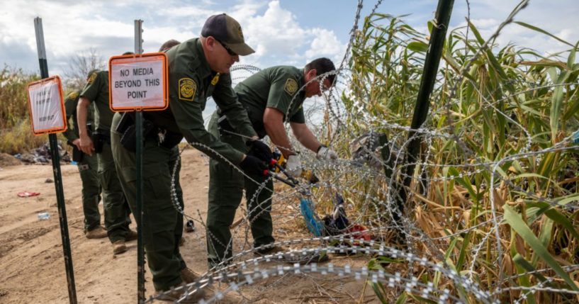 Border Patrol agents cut an opening through razor wire after immigrant families crossed the Rio Grande from Mexico, September 27, in Eagle Pass, Texas.