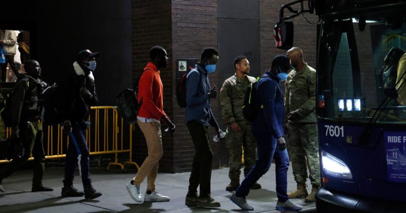 U.S. military personnel keep watch as asylum seekers are transferred via city bus from Port Authority bus terminal to housing facilities in the Bronx and Queens on May 15 in New York City.