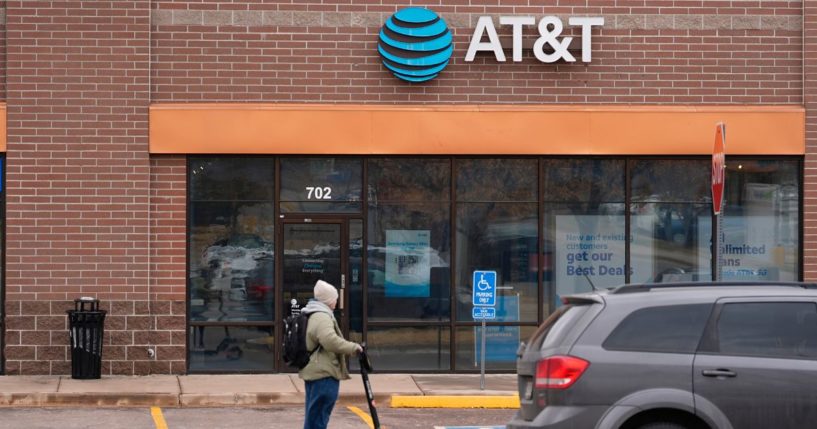 a man riding an electric scooter past an AT&T store