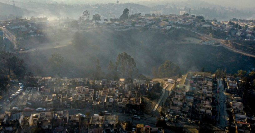 Smoke raises from burned-out houses Saturday after a forest fire reached the Villa Independencia neighborhood in Vina del Mar, Chile.