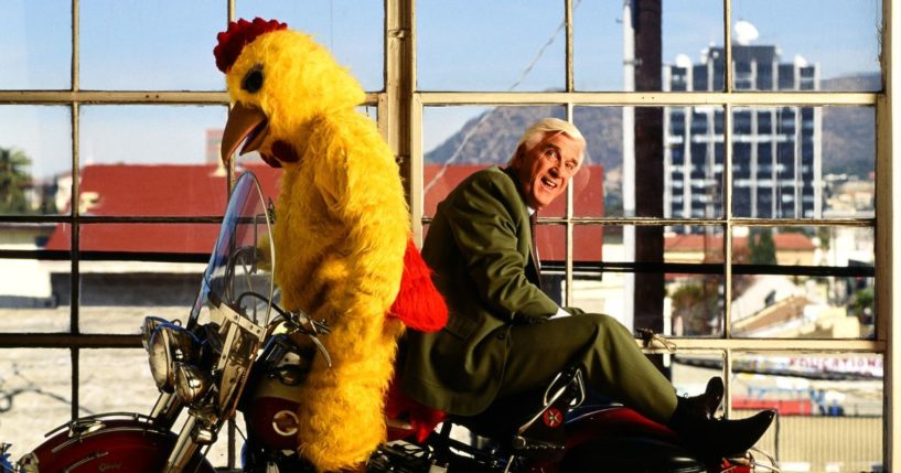 Actor Leslie Nielsen with a motorcycle and a man in a chicken suit in Hollywood, California, in 1992.