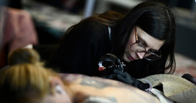 French tattoo artist Norma tattoos a woman's back during the Tattoo Planetarium 2024 edition in Paris, France, on Feb. 2.