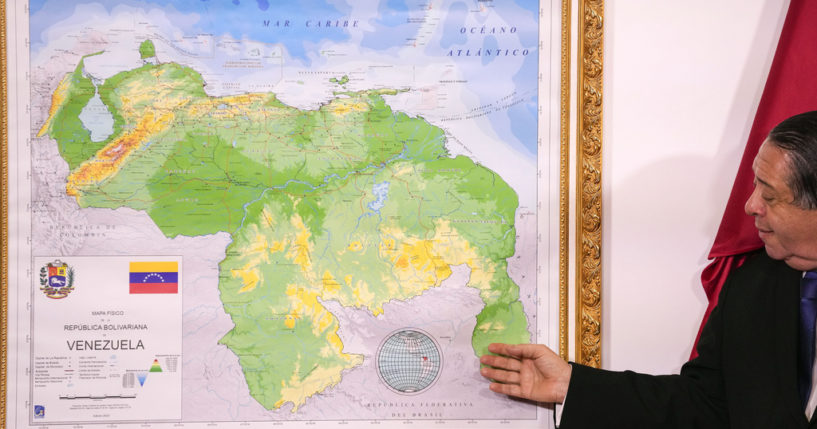 Chairman of the Special Commission for the Defense of Guyana, Essequibo Hermann Escarra, stands next to Venezuela's new map that includes the Essequibo territory, a swath of land that is administered and controlled by Guyana but claimed by Venezuela.